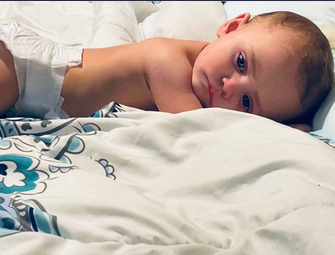 Remington Todd is registered to the contest to win money with this photo: abdomen, baby, baby_products, baby_sleeping, baby_toddler_clothing, bed, bed_sheet, bedding, bedtime, chest, child, comfort, eyelash, human_leg, linens, pattern, person, room, t_shirt, textile