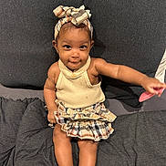 Iniyah is registered to the contest to win money with this photo: toddler, child, smile, headband, skirt, sitting, toy, couch, fabric, cute, happy, indoors, person, clothing, playful, baby, skin, foot, arm, portrait