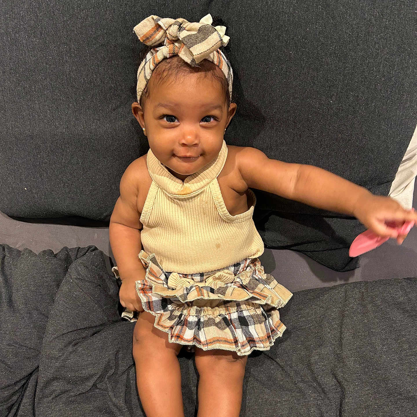 Iniyah is registered to the contest to win money with this photo: arm, baby, child, clothing, couch, cute, fabric, foot, happy, headband, indoors, person, playful, portrait, sitting, skin, skirt, smile, toddler, toy