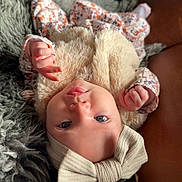 Gabby joined the competition — help win amazing prizes! baby, infant, face, headband, bow, clothing, fur, floral_pattern, hand, skin, eyes, mouth, lying_down, blanket, texture, soft, cute, portrait, child, indoor