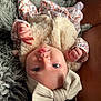 baby, infant, face, headband, bow, clothing, fur, floral_pattern, hand, skin, eyes, mouth, lying_down, blanket, texture, soft, cute, portrait, child, indoor