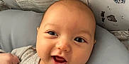 George is registered to the contest to win money with this photo: baby, infant, smiling, blanket, gray_blanket, cushion, face, cute, happy, indoors, clothing, onesie, patterned_clothing, head, baby_bed, bear_pattern, child, portrait, closeup, resting