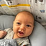 baby, infant, smiling, blanket, gray_blanket, cushion, face, cute, happy, indoors, clothing, onesie, patterned_clothing, head, baby_bed, bear_pattern, child, portrait, closeup, resting