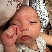 George is registered to the contest to win money with this photo: baby, sleeping, infant, close_up, onesie, blanket, pillow, face, hand, peaceful, newborn, skin, soft, indoors, rest, cute, child, portrait, comfort, sleep