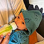 George joined the competition — help win amazing prizes! baby, bottle, feeding, hoodie, dinosaur, infant, child, person, clothing, hand, milk, cute, cozy, warm, indoor, portrait, care, feeding_time, soft, comfort