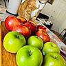 Soju is registered to the contest to win money with this photo: cat, orange_tabby, apple, green_apple, red_apple, fruit, wooden_board, table, indoor, collar, curious, domestic_cat, household, family_photo, door, kitchen, background, focus, closeup, pet