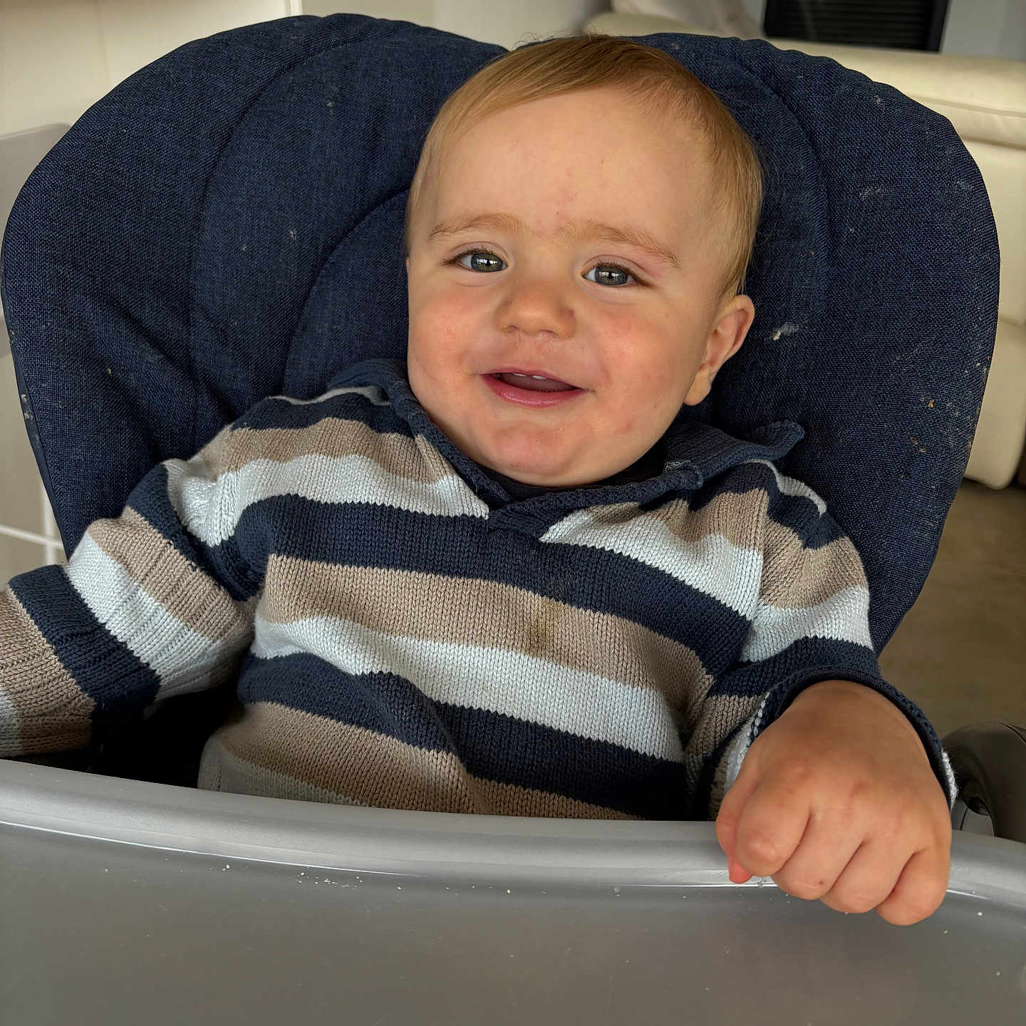 Oscar a rejoint le concours — aidez-le/la à gagner de superbes lots ! baby, casual, child, cozy, cute, expression, face, furniture, hand, happy, high_chair, indoor, living_room, modern, person, portrait, seated, smile, striped_sweater, young_child