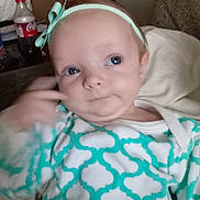 Rosemary joined the competition — help win amazing prizes! baby, child, infant, headband, bow, onesie, patterned_clothing, blue_eyes, hand_gesture, indoor, sofa, cushion, bottle, coca_cola, curious, portrait, face, person, casual, cozy