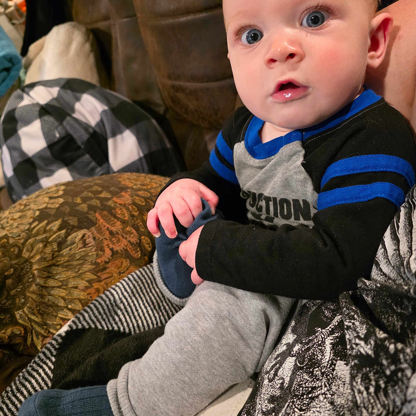 Kayden joined the competition — help win amazing prizes! baby, blanket, blue_eyes, casual, child, closeup, clothing, comfort, couch, curious, cute, face, hand, indoor, infant, pattern, person, portrait, sitting, sock