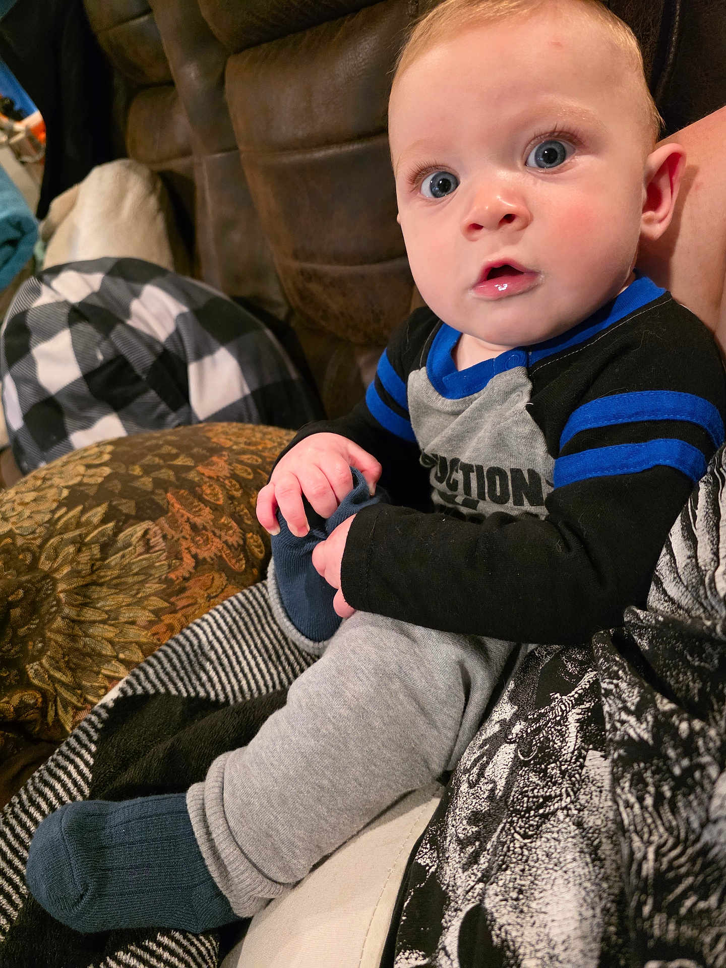 Kayden joined the competition — help win amazing prizes! baby, child, blue_eyes, sitting, sock, hand, face, clothing, blanket, pattern, couch, indoor, portrait, curious, infant, casual, cute, person, comfort, closeup