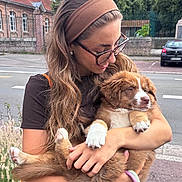 Awaï a rejoint le concours — aidez-le/la à gagner de superbes lots ! woman, puppy, dog, glasses, headband, brown_hair, holding, outdoor, street, sidewalk, greenery, building, happy, smile, pet, leash, casual_clothing, affection, cute, young_adult