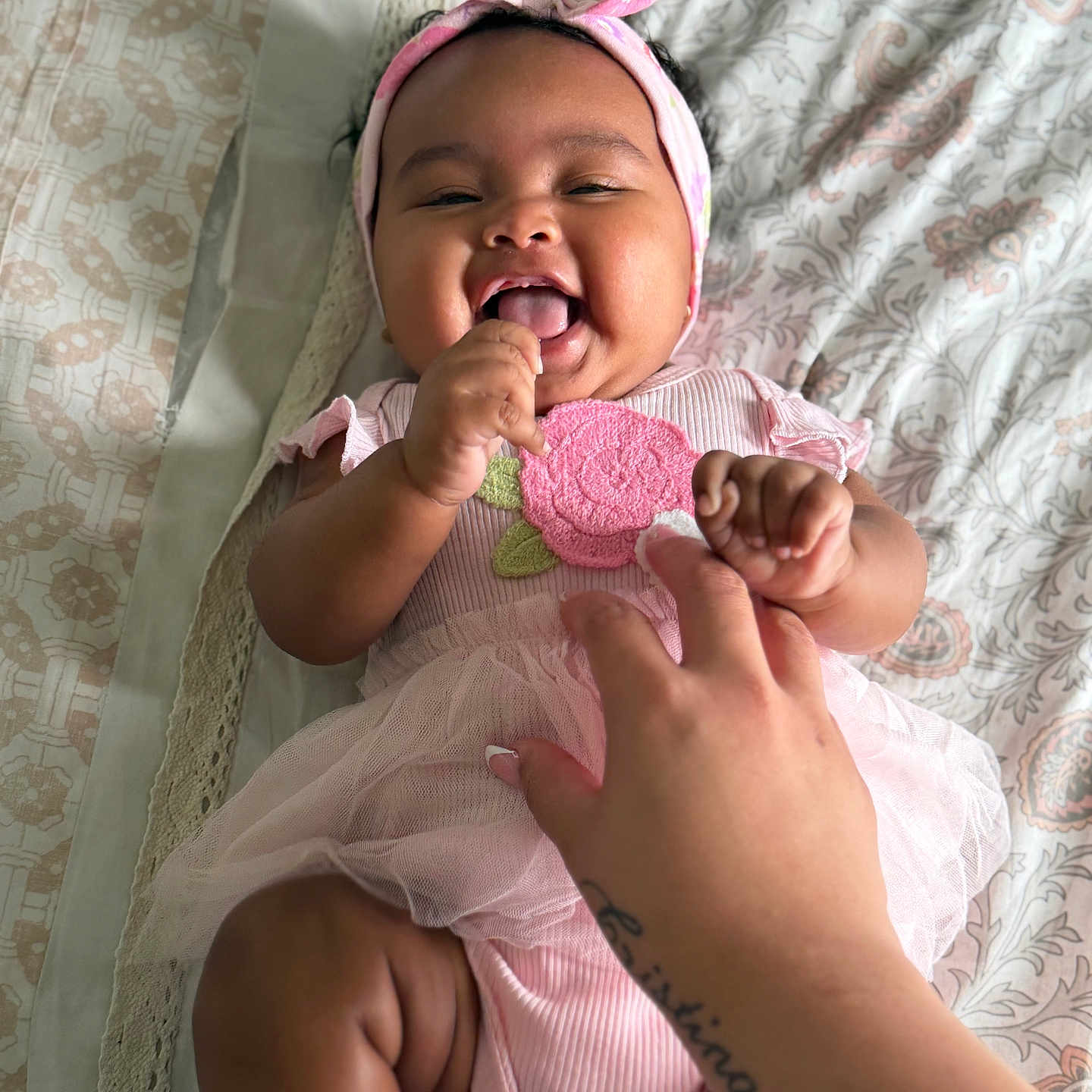 Daelani joined the competition — help win amazing prizes! baby, child, pink_clothing, headband, smile, happy, hand, tattoo, bedspread, pattern, infant, cute, joyful, toddler, person, portrait, lying_down, skin, fingers, indoors