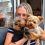 person, dog, yorkshire_terrier, pet, animal, indoor, couch, embrace, smile, happy, fur, face, holding, close_up, home, window, arm, casual, striped_shirt, relaxing