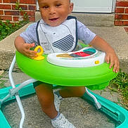 Amar is registered to the contest to win money with this photo: toddler, child, walker, toy, smiling, outdoor, concrete, brick_wall, door, shoes, sneakers, grass, play, baby, person, clothing, happy, cute, young, front_porch