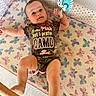 Hannah is registered to the contest to win money with this photo: baby, infant, onesie, camo, playpen, toy, butterfly_pattern, mattress, smiling, child, cute, indoor, person, hand, foot, face, clothing, fabric, happy, lying_down