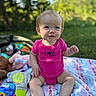 baby, child, infant, smiling, outdoor, garden, picnic, blanket, toys, pink_clothing, onesie, seated, portrait, happy, sunlight, bokeh, grass, trees, playtime, toddler