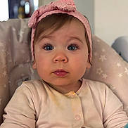 Freya is registered to the contest to win money with this photo: baby, child, pink_bow, headband, high_chair, onesie, face, blue_eyes, curious, seated, indoor, portrait, infant, cute, expression, soft_lighting, clothing, star_pattern, young_child, closeup