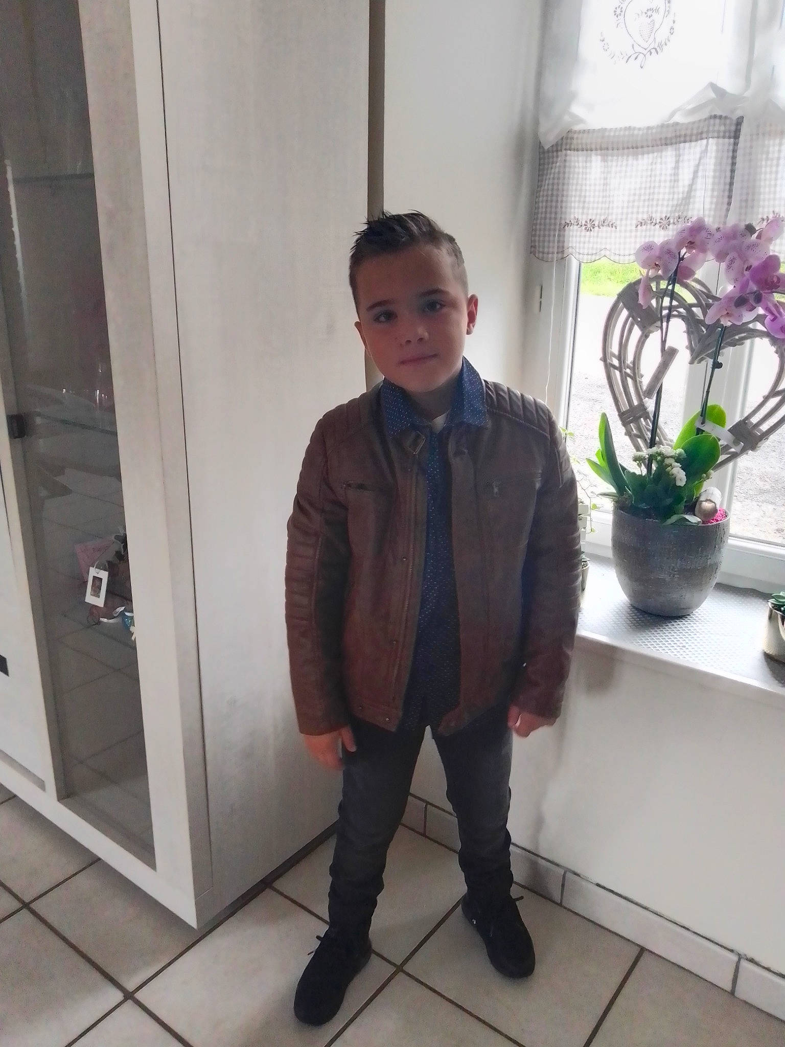 Ethann participe au concours pour gagner de l'argent avec cette photo : blazer, collar, curtain, door, dress_shirt, flooring, flowerpot, formal_wear, houseplant, knee, leg, person, plant, shoulder, sleeve, standing, street_fashion, tie, vase, waist
