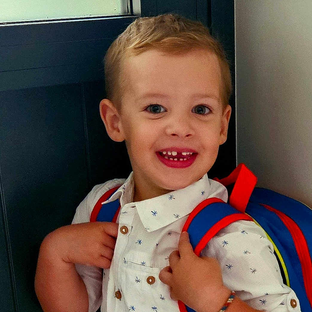 Gabin participe au concours pour gagner de l'argent avec cette photo : accessories, baby, backpack, bag, blonde, bodypart, clothing, door, face, hair, happy, head, mouth, pants, person, photography, portrait, smile, t_shirt, teeth