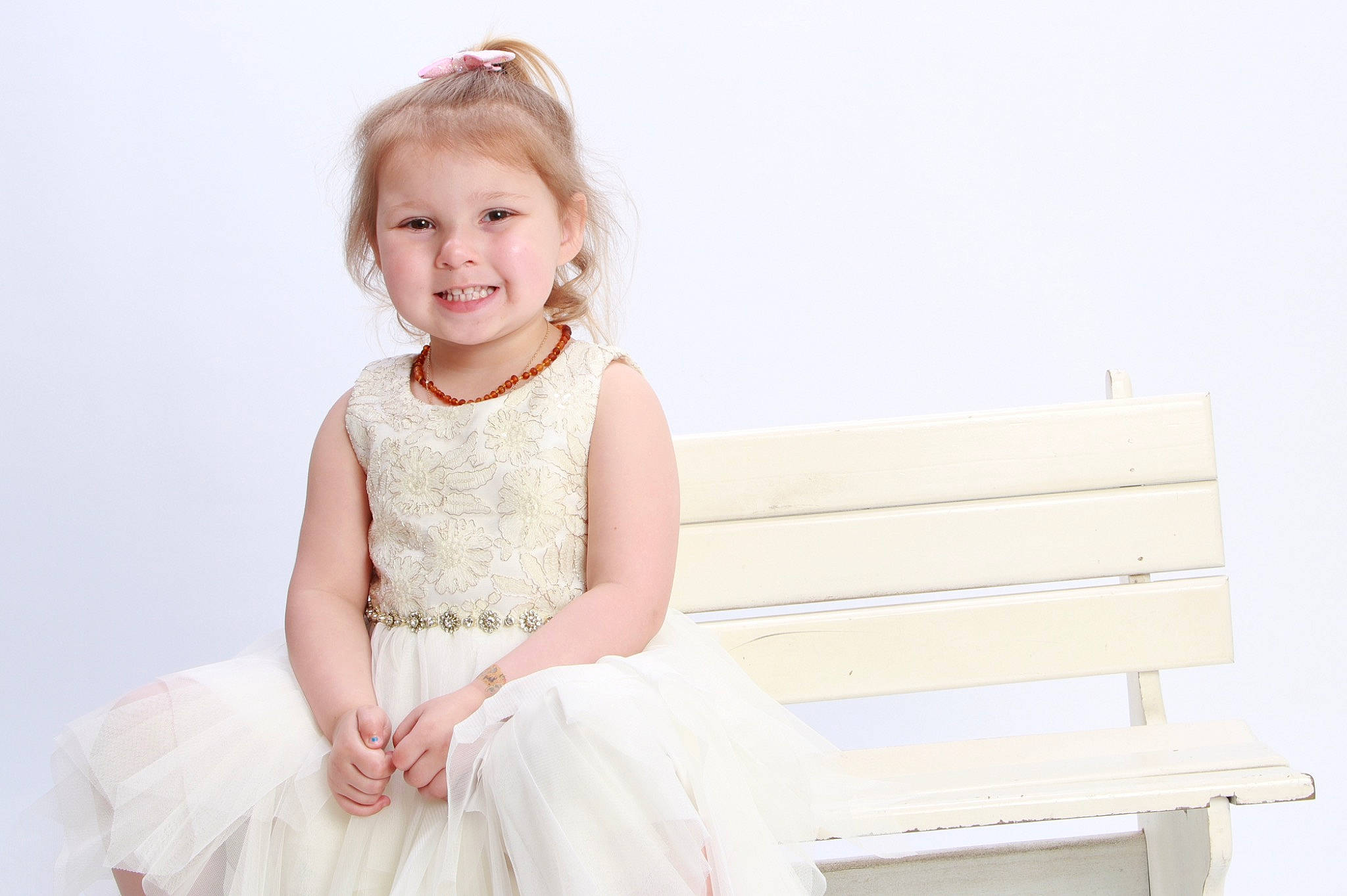 Evie is registered to the contest to win money with this photo: baby_toddler_clothing, bench, bridal_clothing, bridal_party_dress, clothing, day_dress, dress, event, fashion_accessory, fashion_design, flash_photography, formal_wear, gown, hair, happy, human_body, joy, person, sitting, sleeve
