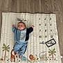 Mateo joined the competition — help win amazing prizes! baby, infant, milestone_blanket, numbers, months, blue_clothing, floor, wooden_floor, animal_prints, giraffe, elephant, lion, palm_tree, blanket, child, cute, lying_down, indoors, person, young_child