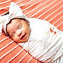 baby, newborn, smiling, sleeping, headband, blanket, floral_pattern, wrapped, pillow, coral_pink, texture, closeup, cute, infant, resting, soft, peaceful, indoors, portrait, child