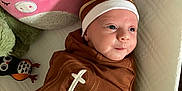 Koraline is registered to the contest to win money with this photo: baby, infant, swaddle, football_blanket, headband, bow, plush_toy, pink_pig, owl_toy, quilted_surface, cute, face, smiling, lying_down, soft_toys, child, indoors, cozy, newborn, playtime