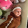 baby, infant, swaddle, football_blanket, headband, bow, plush_toy, pink_pig, owl_toy, quilted_surface, cute, face, smiling, lying_down, soft_toys, child, indoors, cozy, newborn, playtime