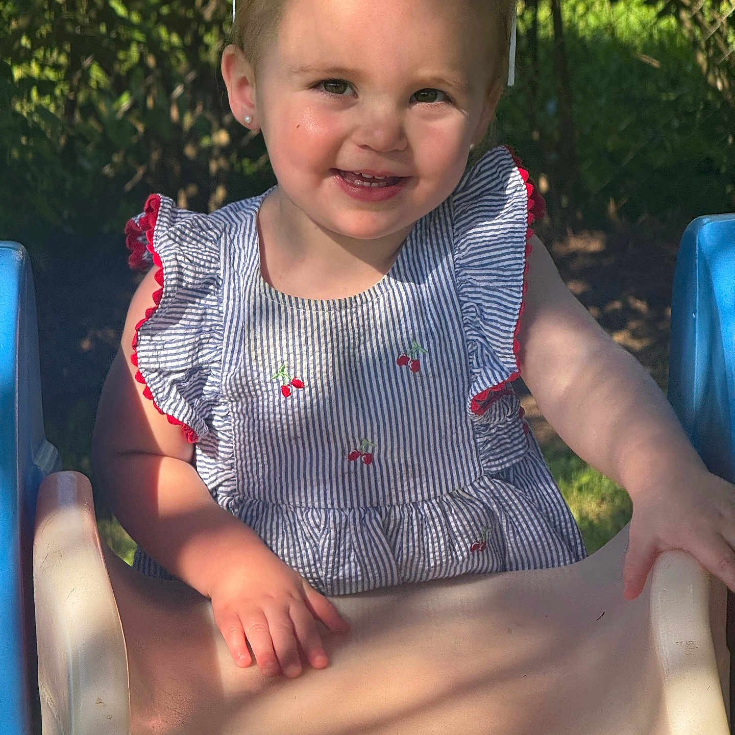 Camden-Rae joined the competition — help win amazing prizes! child, cute, daylight, dress, fence, fun, greenery, hair_bow, happy, nature, outdoor, person, playground, portrait, slide, smile, summer, sunlight, toddler, young_child