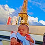 Ella a rejoint le concours — aidez-le/la à gagner de superbes lots ! baby, child, person, eiffel_tower, landmark, sky, cloud, outdoor, daylight, travel, tourist, holding, bib, blanket, arm, watch, bracelet, hand, portrait, expression