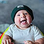 baby, infant, child, smiling, laughing, blue_eyes, beanie, hat, ribbed_shirt, short_sleeve, happy, cute, hands, face, portrait, indoor, blurry_background, young, person, seated