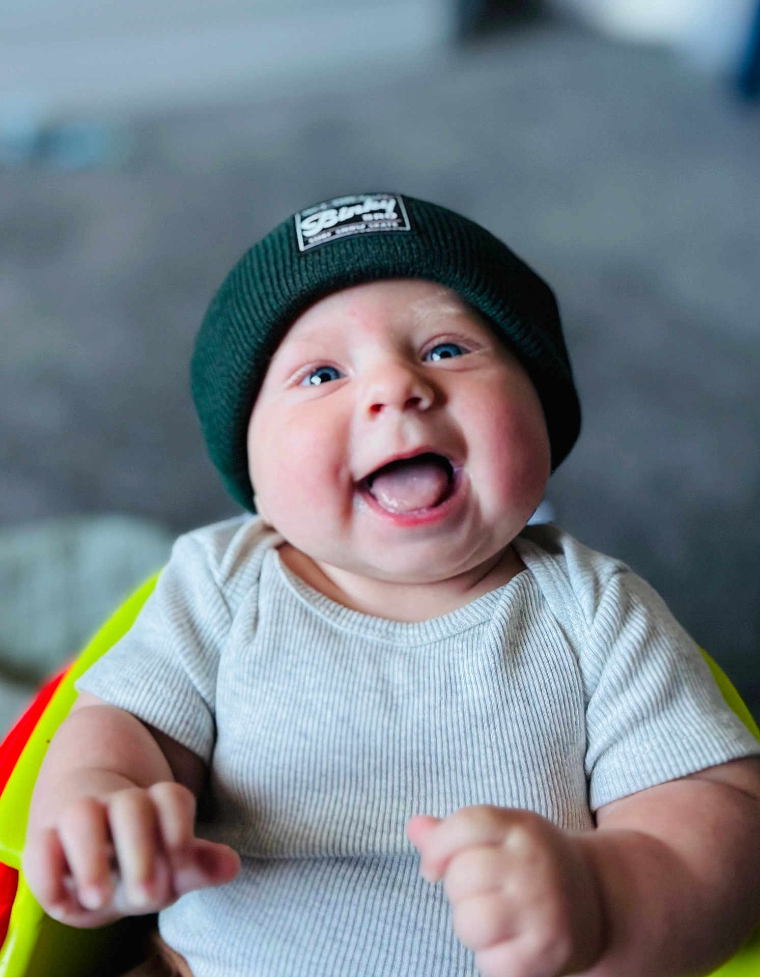 Brennan is registered to the contest to win money with this photo: baby, infant, child, smiling, laughing, blue_eyes, beanie, hat, ribbed_shirt, short_sleeve, happy, cute, hands, face, portrait, indoor, blurry_background, young, person, seated