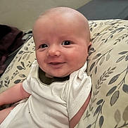 Bronson is registered to the contest to win money with this photo: baby, infant, smile, cushion, onesie, face, skin, child, comfort, happy, portrait, indoors, person, young, cute, expression, head, sitting, clothing, soft