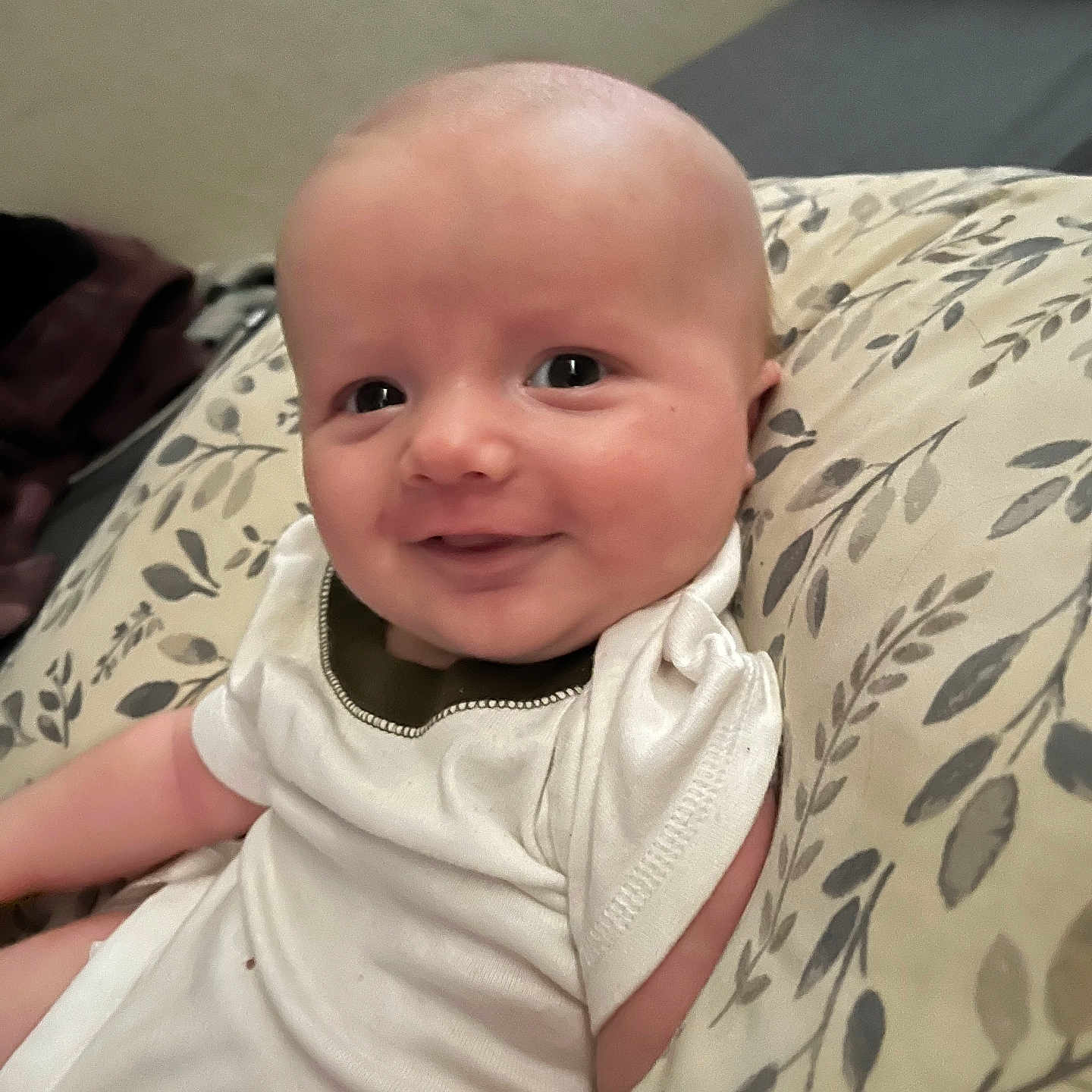 Bronson is registered to the contest to win money with this photo: baby, child, clothing, comfort, cushion, cute, expression, face, happy, head, indoors, infant, onesie, person, portrait, sitting, skin, smile, soft, young