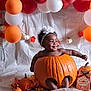 Ruth is registered to the contest to win money with this photo: baby, pumpkin, headband, smile, balloon, orange, white, fall_leaves, autumn, child, decoration, happy, holiday, cute, portrait, indoor, festive, celebration, pumpkin_patch, costume