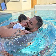 Line Lassave participe au concours pour gagner de l'argent avec cette photo : baby, man, pool, inflatable_ring, water, smile, tattoo, outdoor, sunlight, happy, family, floating, summer, relaxation, skin, person, head, face, love, leisure