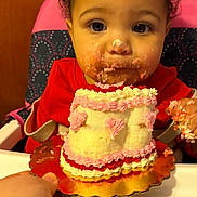 Annalise joined the competition — help win amazing prizes! toddler, child, cake, frosting, messy_face, high_chair, red_clothing, pink_frosting, hand, food, celebration, birthday, sweet, cream, cute, indoor, person, face, happy, curly_hair