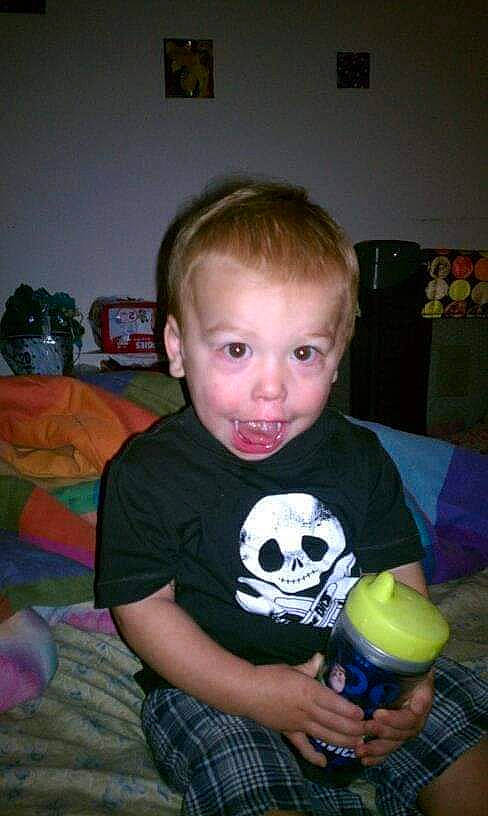 Maddox is registered to the contest to win money with this photo: arm, ball, child, couch, fun, holiday, party, pattern, person, picture_frame, plaid, play, room, sitting, sleeve, smile, soccer_ball, t_shirt, toddler, toy