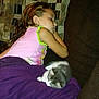 child, sleeping, kitten, blanket, couch, indoor, resting, cozy, purple_blanket, patterned_pillow, cute, pet, nap, calm, young, comfort, home, relaxation, animal, together