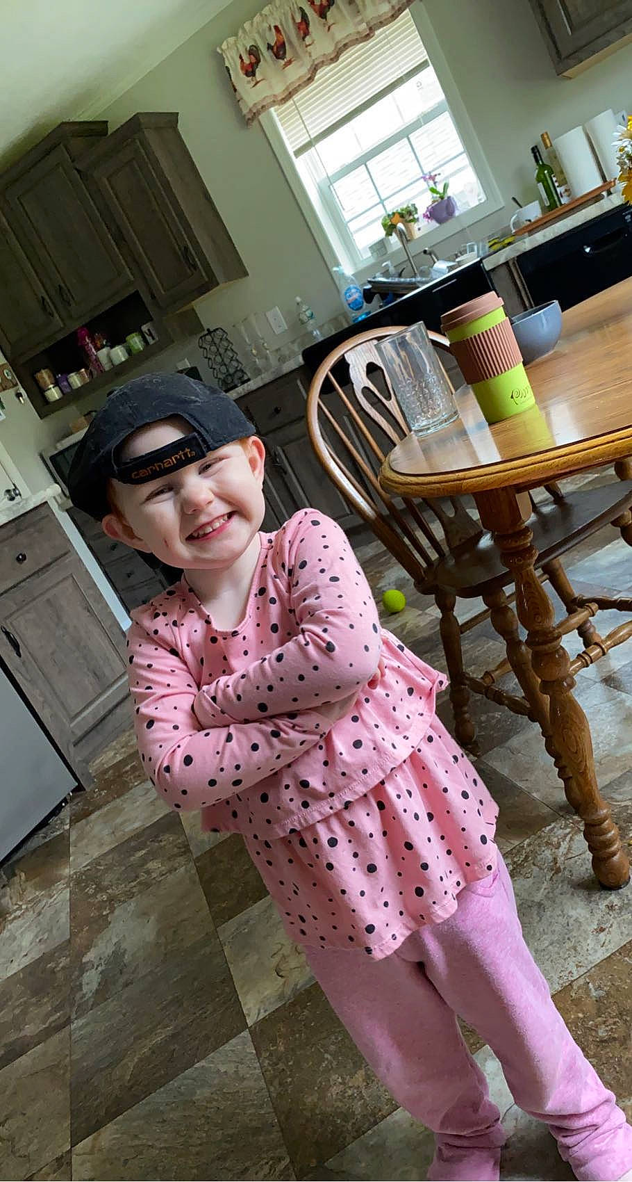 Melanie is registered to the contest to win money with this photo: chair, child, fashion_design, floor, flooring, fun, hardwood, headwear, human_leg, joy, leg, leisure, outdoor_furniture, pattern, person, pink, sitting, sleeve, smile, table