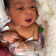 Amiri is registered to the contest to win money with this photo: newborn, baby, infant, hospital, blanket, iv_line, wristband, face, hand, medical, bed, soft, cozy, wrapped, cute, person, skin, indoors, healthcare, lying_down