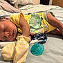 baby, sleeping, bed, yellow_onesie, dinosaur_print, mittens, pacifier, blanket, pillow, infant, cute, peaceful, child, skin, foot, hand, indoors, rest, comfort, soft