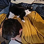 bed, black_and_white_cat, blanket, blue_bedding, casual, cat, comfort, cozy, glasses, hair, indoor, notebook, person, phone, relaxation, resting, sleepy_cat, study, writing, yellow_blanket