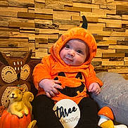 Alessio a rejoint le concours — aidez-le/la à gagner de superbes lots ! baby, infant, pumpkin_costume, orange_costume, hood, three_months_sign, milestone_sign, owl_pillow, squirrel_figurine, wooden_wall, autumn_decor, fall_theme, cute, smile, portrait, sitting, plush_toy, mushrooms, black_leggings, decorative_pumpkin