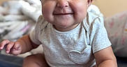 Ava joined the competition — help win amazing prizes! baby, infant, smile, grin, cute, chubby_cheeks, sitting, onesie, indoor, bed, blanket, face, expression, hands, feet, skin, hair, child, portrait, happy