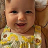 baby, infant, child, smiling, happy, portrait, closeup, face, eyes, bow, headband, sunflower, dress, overalls, floral_pattern, button, sitting, bedding, stuffed_toy, indoor