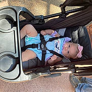 Oakley joined the competition — help win amazing prizes! baby, child, stroller, infant, portrait, outdoor, sitting, lying_down, smiling, face, pink_bow, striped_clothing, romper, safety_harness, carriage, sunlight, pavement, playful, candid, photography