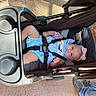 baby, child, stroller, infant, portrait, outdoor, sitting, lying_down, smiling, face, pink_bow, striped_clothing, romper, safety_harness, carriage, sunlight, pavement, playful, candid, photography