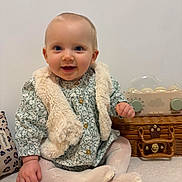 Sienna a rejoint le concours — aidez-le/la à gagner de superbes lots ! baby, child, smiling, blue_eyes, vest, tights, sitting, carpet, toy, wicker_basket, indoor, cute, happy, portrait, person, infant, clothing, furniture, home, cozy