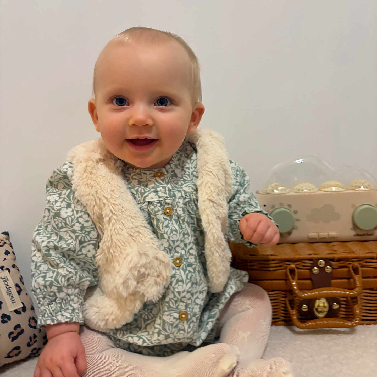 Sienna a rejoint le concours — aidez-le/la à gagner de superbes lots ! baby, child, smiling, blue_eyes, vest, tights, sitting, carpet, toy, wicker_basket, indoor, cute, happy, portrait, person, infant, clothing, furniture, home, cozy